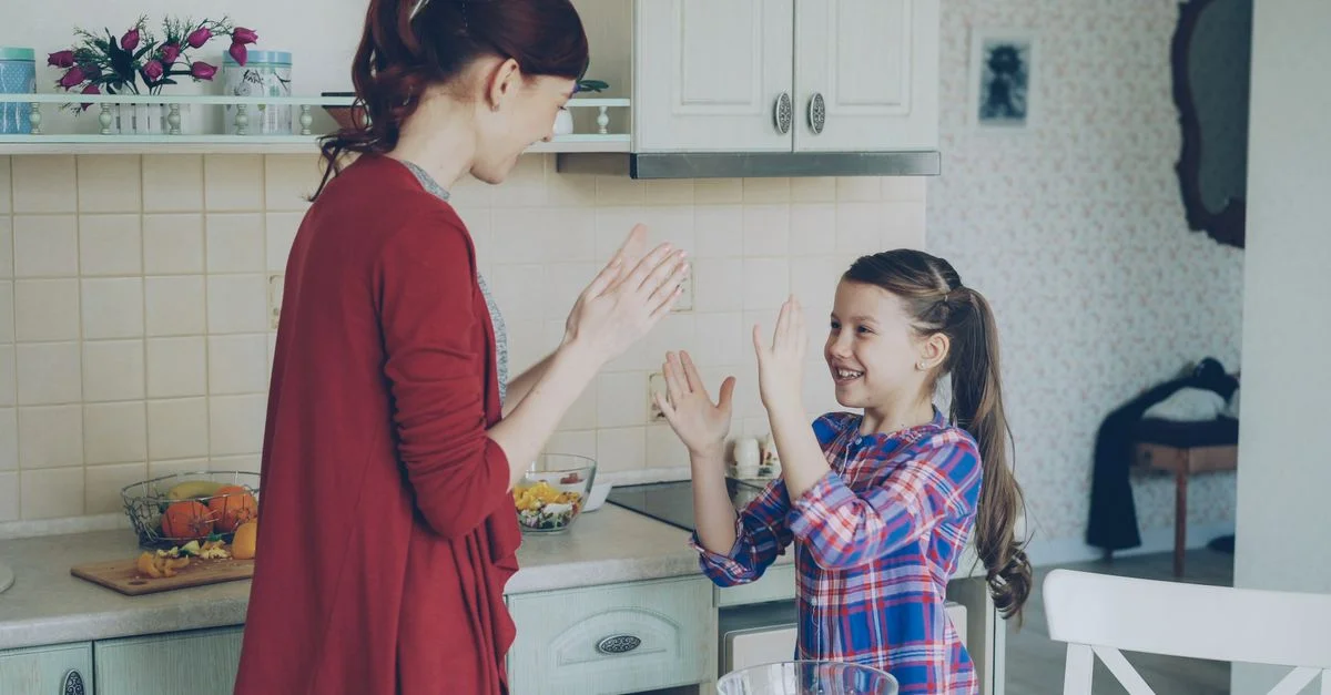 Mère et fille jouant et riant ensemble dans un cadre de cuisine douillet.