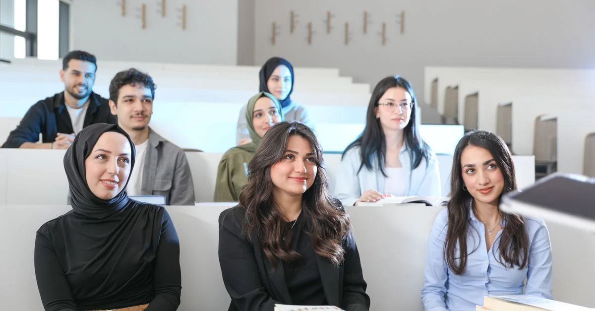 Groupe d'étudiants divers dans une salle de classe universitaire pendant un cours, engagés et attentifs.