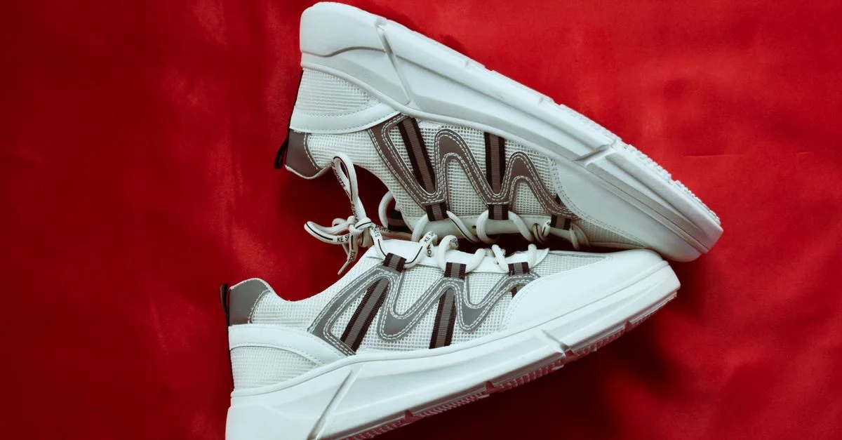 Vue en gros plan de baskets blanches modernes sur un fond rouge vif, mettant en avant un style contemporain.