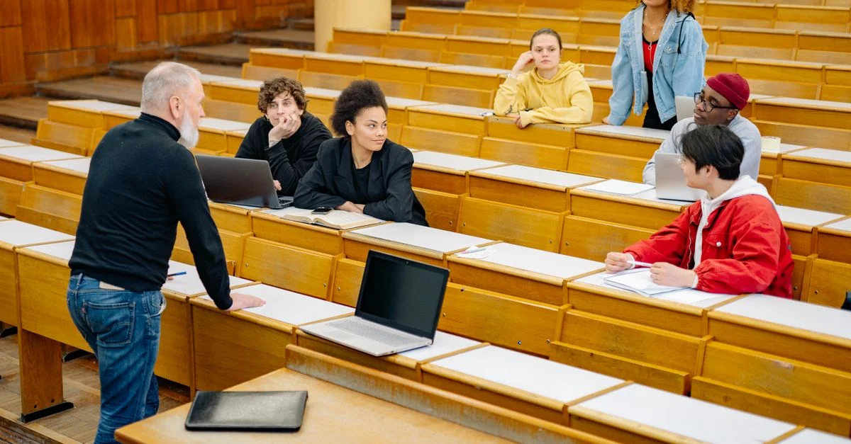 Étudiants écoutant activement et s'engageant dans un cadre de conférence universitaire, illustrant la diversité.