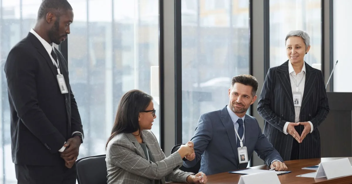 Un groupe diversifié de professionnels se serrant la main lors d'une réunion d'affaires dans un bureau moderne.